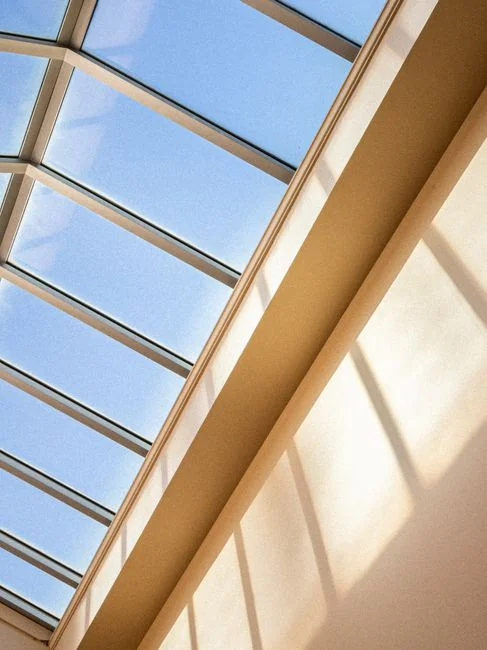Une femme adulte vêtue d’une combinaison rouge utilise un aspirateur dans un intérieur moderne, concentrée sur des tâches de nettoyage.